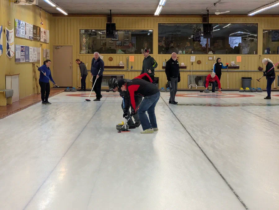Glengarry Pipe Band members sweeping ice at the Curling Bonspiel
